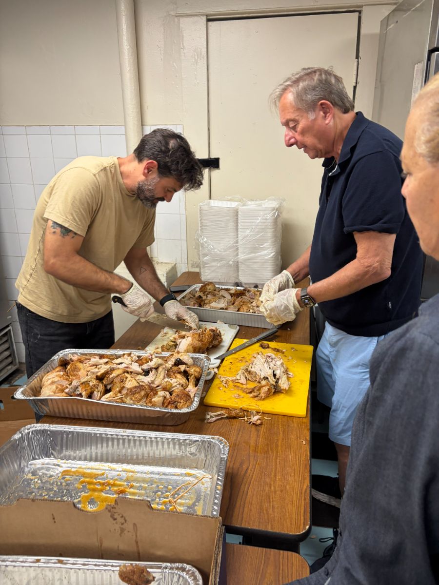 Volunteers carving roast chicken in the CSA Kitchen