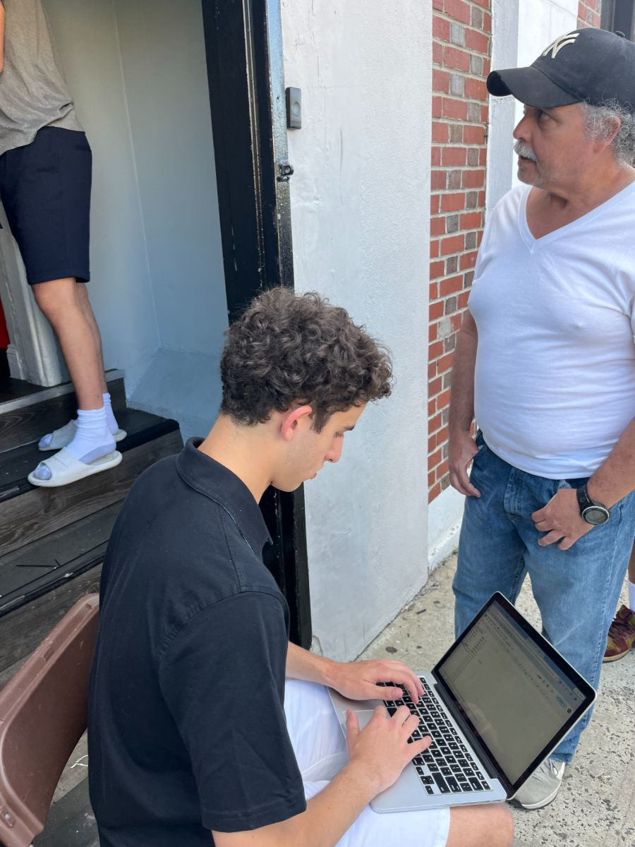 A founder logging details on a laptop with a community member at a delivery